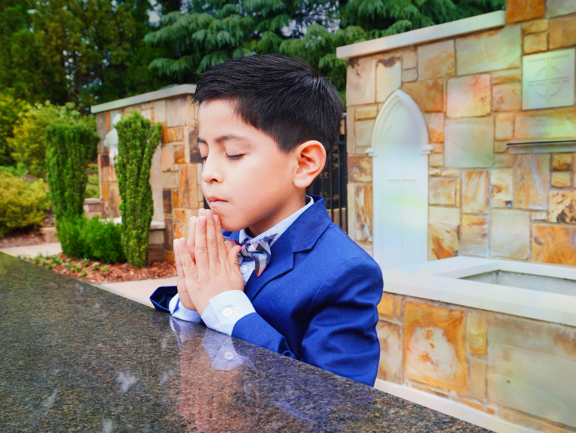 Close portrait of a boy in a blue suit praying outdoors
