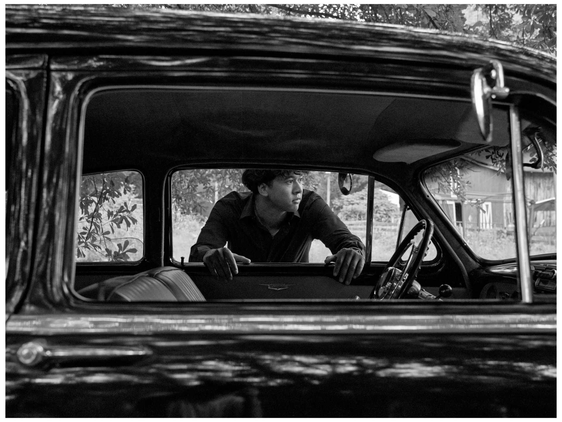 Black and white portrait framed through a classic car window