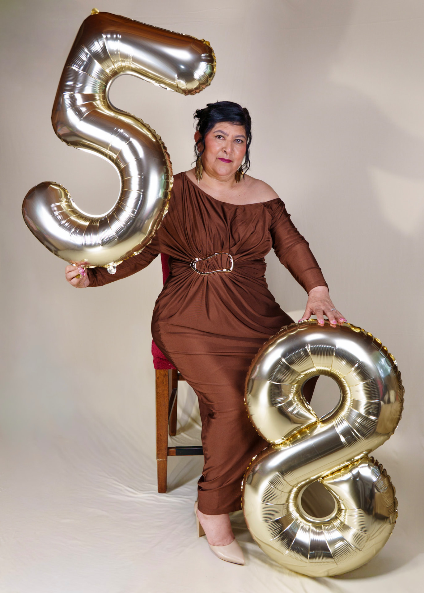 Seated studio portrait with gold number balloons
