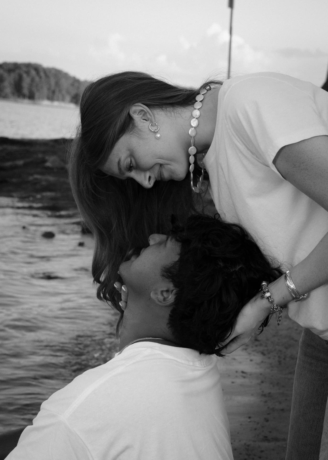 Black and white portrait of a woman leaning over her partner by the shore