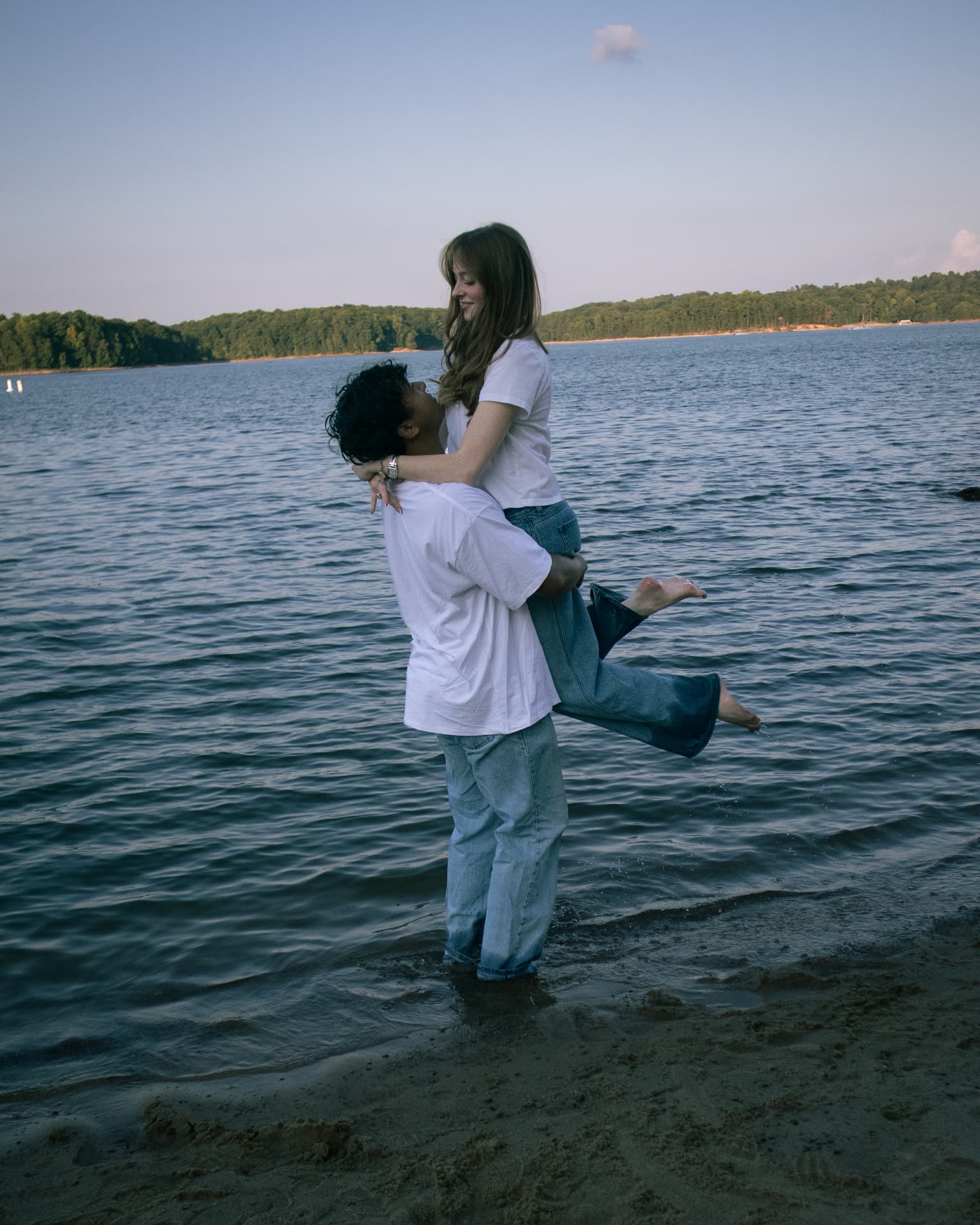 Man lifting his partner in the shallow lake water at golden hour