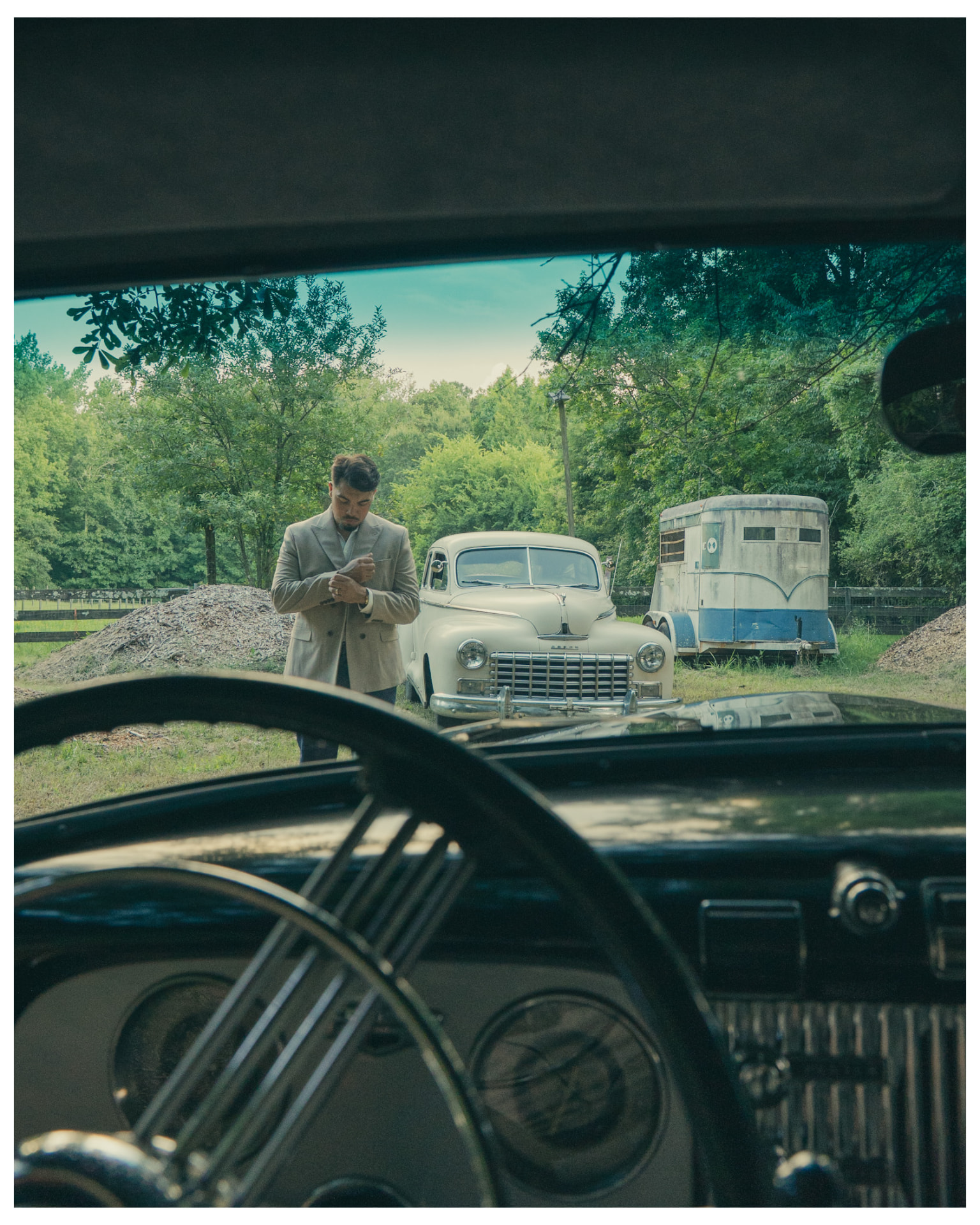View through a vintage windshield of a man beside a cream car