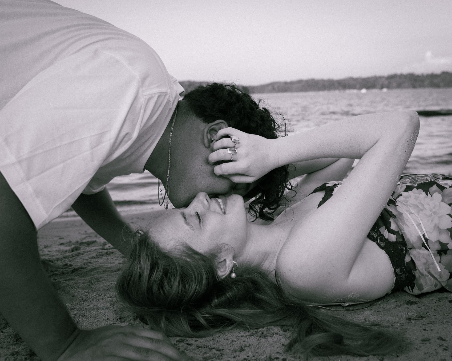 Black and white couple laughing together on the sand at the lake
