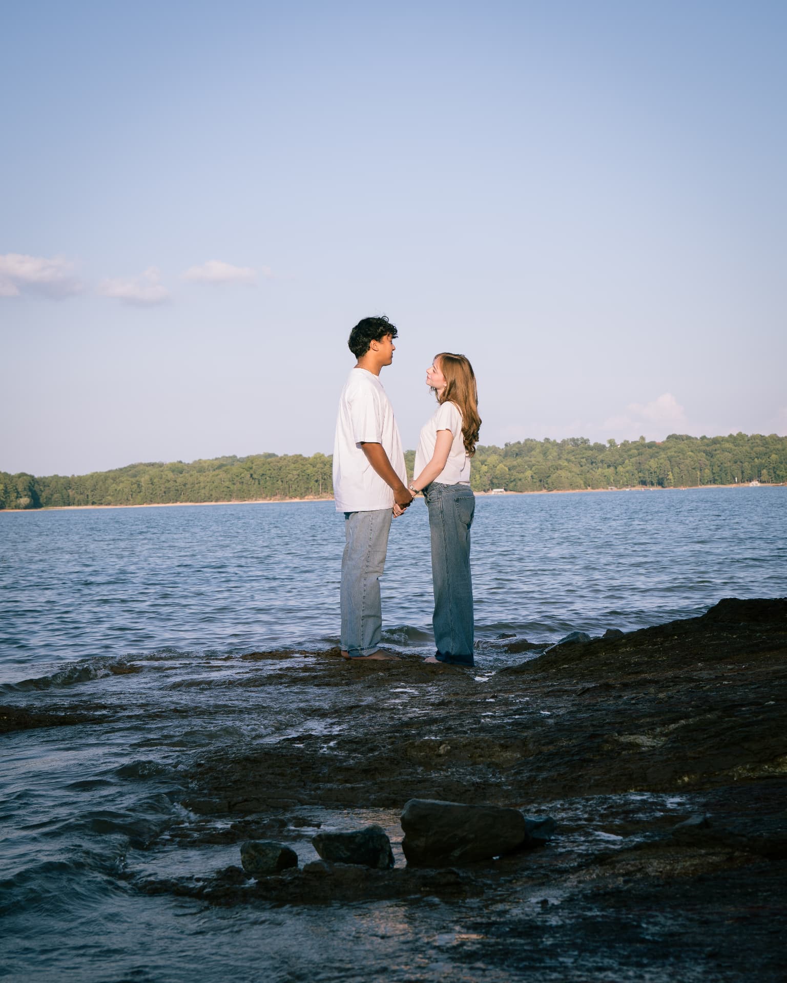 Couple holding hands at the edge of Lake Lanier at golden hour in North Georgia