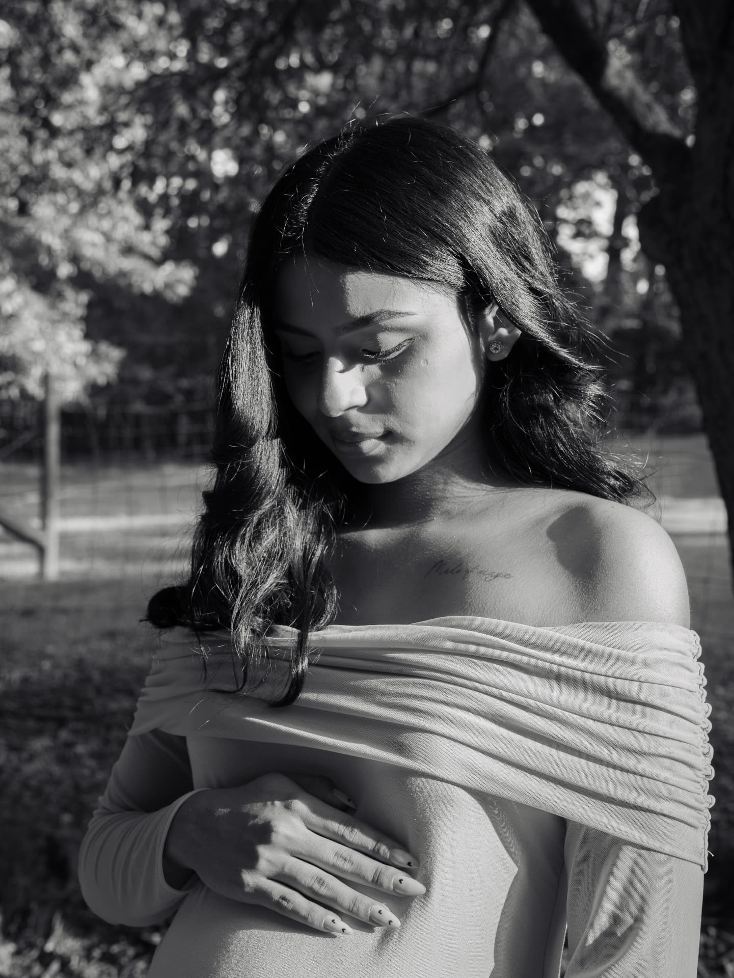 Black and white close maternity portrait of a mother looking down at her bump