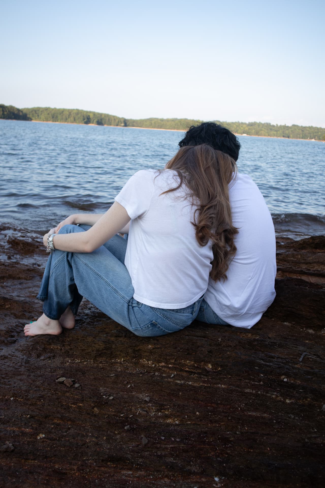 Couple sitting together on the rocks watching the lake