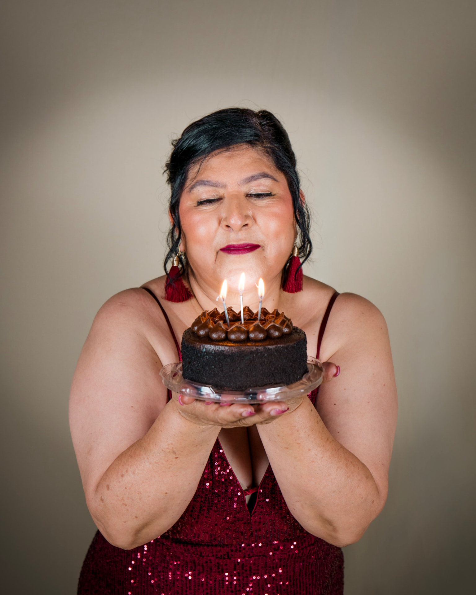Woman blowing out candles on a chocolate cake during a studio birthday session