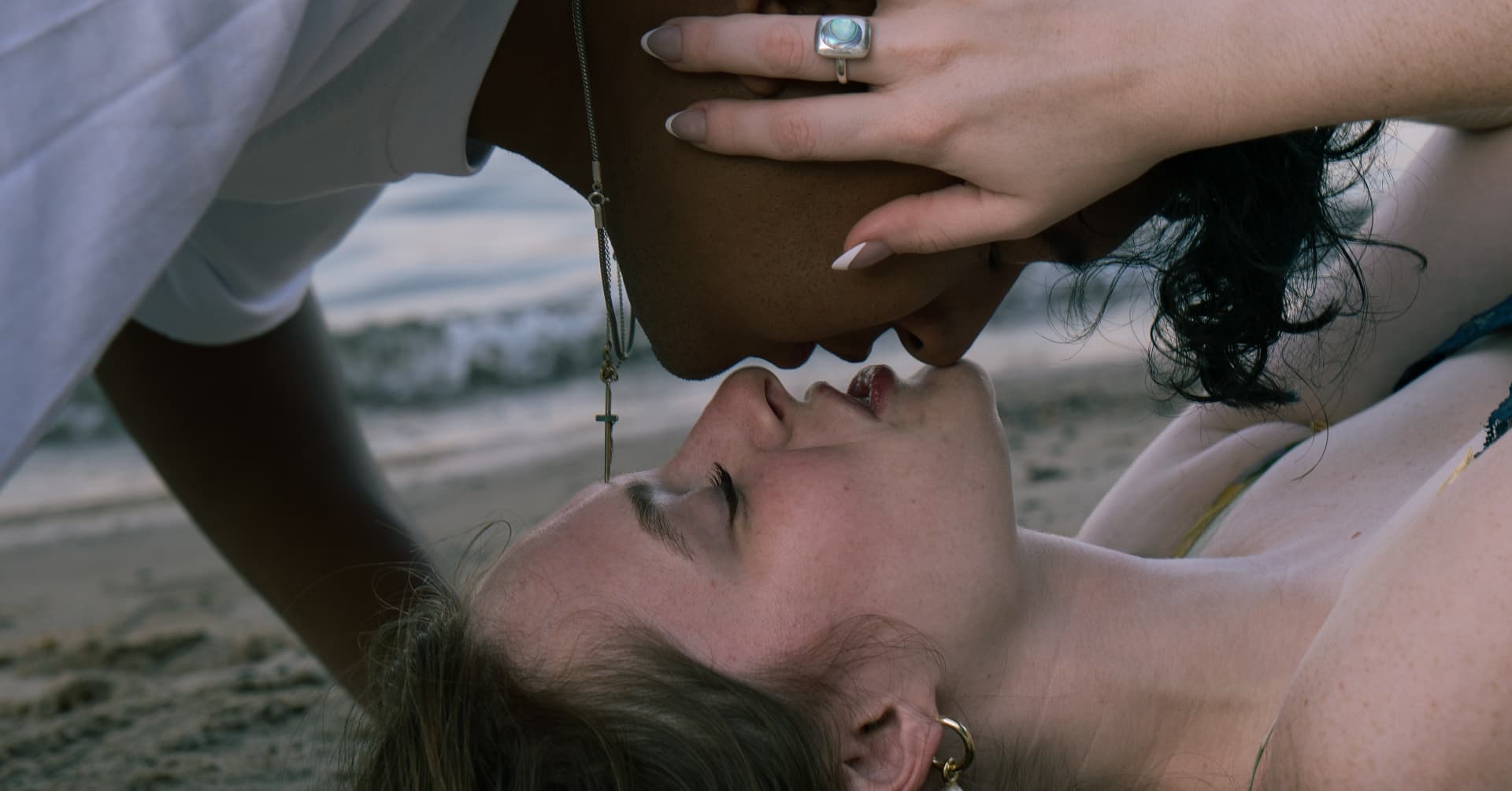 Close romantic portrait of a couple kissing on the sand at dusk